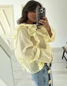 Dettaglio della camicetta in chiffon giallo chiaro con volant a strati e maniche a campana