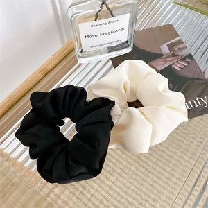 French style satin scrunchies in black and beige displayed on a glass table setup