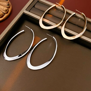 Detailed view of large gold and silver oval metal hoop earrings on a dark display tray