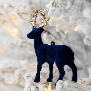 Blue flocked reindeer ornament with golden glitter antlers on a snowy Christmas tree