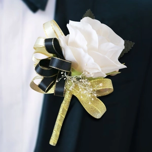 Boutonnière rose blanche élégante avec ruban noir et or sur revers de costume de mariage