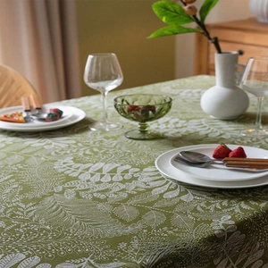 Detail of green linen tablecloth with white fern leaves and textured fabric