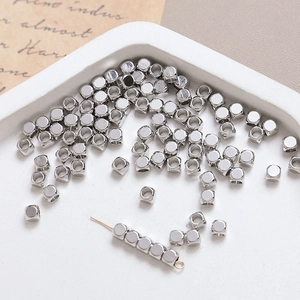 Macro shot of silver square spacer beads in a white tray for DIY jewelry making