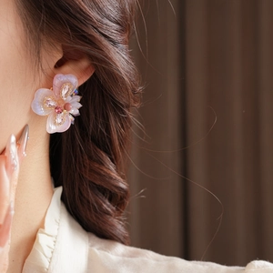 Détail de la boucle d'oreille fleur en cristal avec dégradé rose-violet sur le mannequin