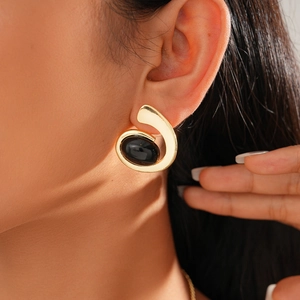 Detail of vintage gold metal spiral stud earring with a black oval resin gemstone