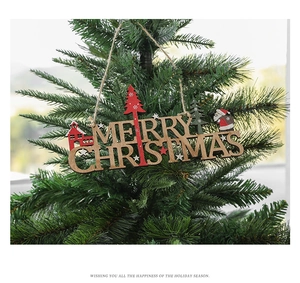 Close-up of laser-cut wooden Merry Christmas sign hanging on a festive tree branch