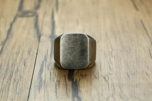Close-up of square face signet ring with vintage silver finish on a wooden surface
