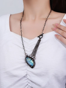 Detailed view of large natural labradorite stone pendant on bronze chain worn by a model