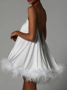Détail de robe mini en satin blanc avec bretelles chaîne et ourlet en plumes d'autruche