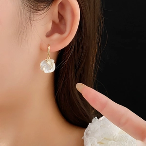 Close-up of vintage flower earrings in gold plating with white shell petals on model