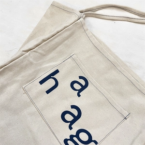 Detailed view of heavy-duty cream canvas tote bag with contrast stitching and navy lettering