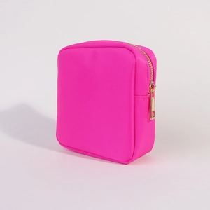 Detailed view of pink nylon cosmetic bag with premium gold zipper on white background