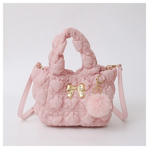 Detail of pink quilted cloud bag featuring golden bow clasp and soft fur ball charm