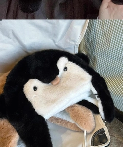 Detail view of plush penguin trapper hat showing soft faux fur texture and ear flaps