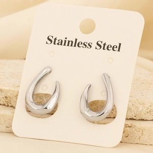 Vue macro des boucles d'oreilles en forme de C en acier inoxydable sur carte beige