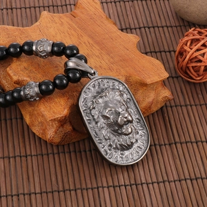 Detailed view of vintage lion head pendant with black beads on a rustic wood base