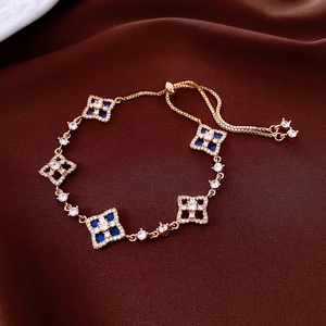 Detail of adjustable gold bracelet with blue flower charms and sparkling zircons