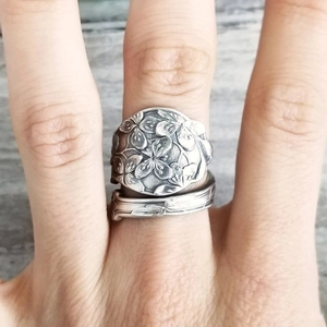Vintage silver-tone spoon ring with intricate 3D floral relief on a female hand