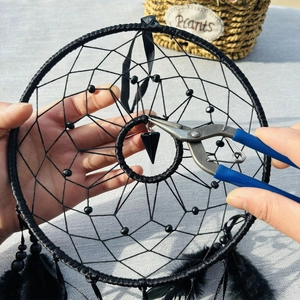 DIY black dream catcher with hexagonal cone pendant and feathers being assembled by hand