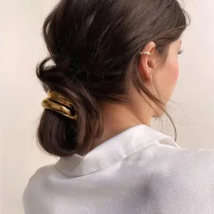 Detailed view of a thick gold metal hair ring accessory worn on a low ponytail