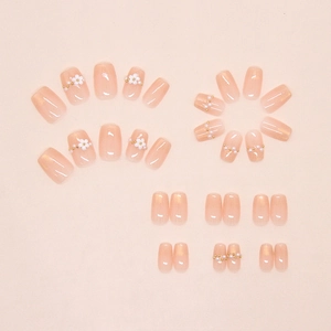 Detailed flat lay of pink cat-eye press-on nails with pearl flower and gold bead accents