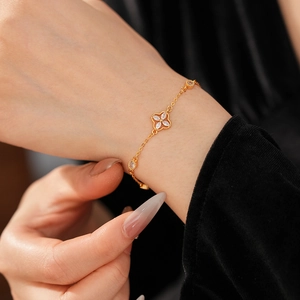 Close-up of gold flower bracelet with zircon stones worn on wrist with black sleeve