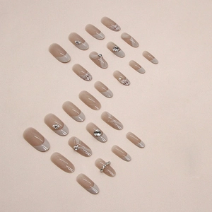 Pink oval press-on nails set with French tips, pearls, rhinestones and plaid patterns