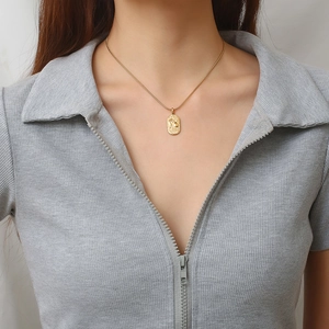 Golden oval pendant necklace with zodiac engraving on snake chain worn by a model