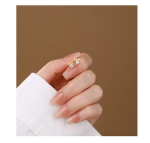 Close-up of gold bow earrings with clear cubic zirconia held at fingertips