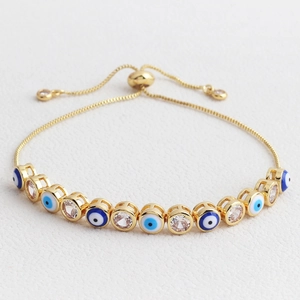 Detail of adjustable gold-plated evil eye bracelet with colorful zircon stones on white leather