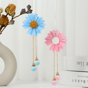 Detail of handmade daisy car charms in pink and blue with gold chains and crystal beads
