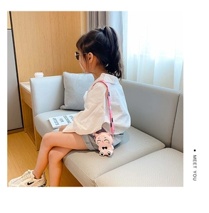 Girl wearing pink cat-shaped silicone crossbody bag in a cozy home setting