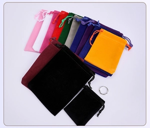 Multi-colored velvet drawstring jewelry pouches in various sizes with ring for scale