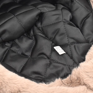 Macro shot of quilted polyester lining and faux fur trim with care label on a winter hat