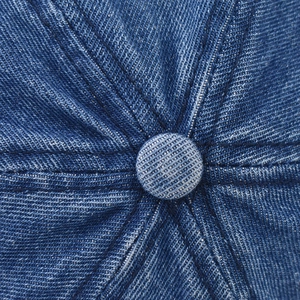 Close-up of the crown on a washed denim baseball cap with reinforced stitching details