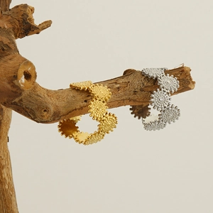 Close-up of gold and silver gear-textured rings displayed on natural wood branches