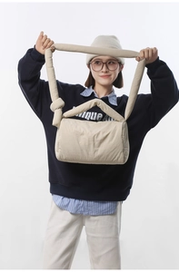 Detail of cream quilted nylon crossbody bag featuring a soft knotted shoulder strap