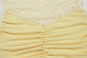 Detail of light yellow dress with floral lace stitching and ruched fabric texture