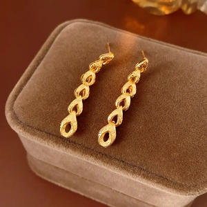 Gros plan de boucles d'oreilles dorées à pampilles sur une boîte à bijoux en velours brun