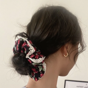 Floral scrunchie with red roses and white lace trim shown on a messy bun hairstyle