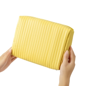 Handheld quilted yellow leather makeup bag with zip closure on white background