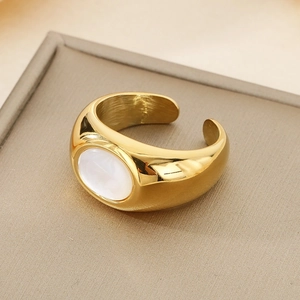 Dettaglio di un anello dorato largo con intarsio in madreperla ovale e finitura lucida