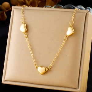 Elegant gold-plated stainless steel necklace with three heart pendants on a display