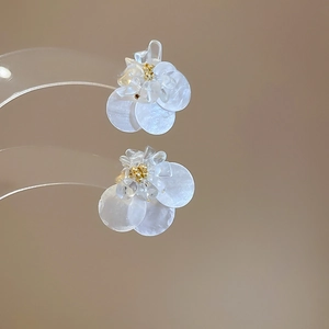 Dettaglio di orecchini a fiore bianco con petali in madreperla e perle di cristallo