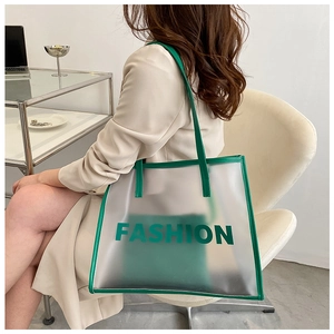 Detail of green transparent fashion tote bag featuring white lettering and leather trim