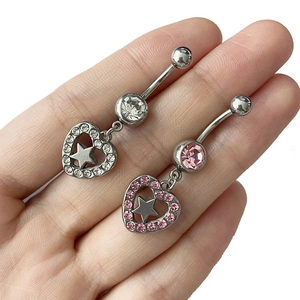 Détail de piercings de nombril cœur et étoile avec zircones claires et roses