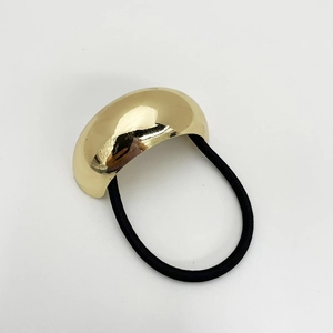 Detailed close-up of a glossy gold geometric metal buckle on a black elastic hair tie