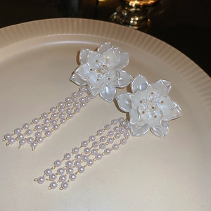 Vue macro de boucles d'oreilles fleurs blanches avec de longs pompons en perles