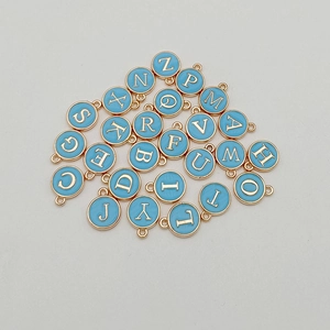 Macro shot of light blue enamel round gold-rimmed alphabet charms for DIY jewelry making