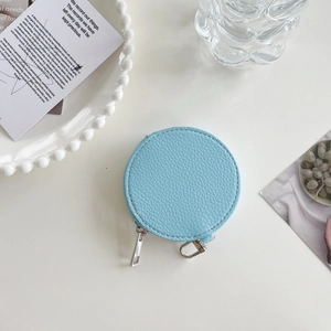 Detailed view of light blue leather round coin purse with silver zipper and pebble texture